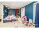 A blue walled bedroom features a bed, red shelving, and a light-colored carpet at 335 Summit Se Ct, Concord, NC 28025