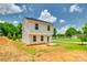 Back of a two-story white home with a black roof and green trees under a cloudy blue sky at 463 W Barr St, Lancaster, SC 29720