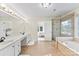 Bright bathroom features a soaking tub under a large window and a tiled glass-enclosed shower with double vanity at 5310 Addington Ct, Charlotte, NC 28277