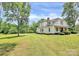 Inviting white farmhouse with a lush green lawn and mature trees at 604 Ferguson Ridge Rd, Gastonia, NC 28052
