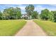 Scenic view of a white farmhouse with a long driveway and mature trees, offering privacy and charm at 604 Ferguson Ridge Rd, Gastonia, NC 28052