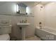 Clean bathroom featuring a pedestal sink, white tile walls, and a classic bathtub with shower at 613 E Ridge St, Kings Mountain, NC 28086
