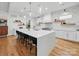 Spacious kitchen featuring a large quartz island with seating, pendant lighting, white cabinetry, and modern marble backsplash at 708 Cross Trail Dr, Charlotte, NC 28204