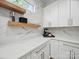 Bright kitchen area featuring quartz countertops, white cabinets, stainless steel hardware, and open shelving, optimizing organization and functionality at 708 Cross Trail Dr, Charlotte, NC 28204
