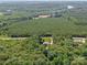 An elevated view shows a home and its outbuildings nestled among dense trees and lush land at 733 Killian Rd, Stanley, NC 28164