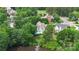 Aerial view showcasing a lovely home with a pool surrounded by lush trees near a lake and golf course at 7704 Ninth Fairway Ln, Mint Hill, NC 28227