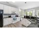 Open kitchen with white cabinets, black countertops, modern appliances, and a breakfast bar area at 7704 Ninth Fairway Ln, Mint Hill, NC 28227