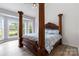 Spacious main bedroom with four-poster bed, light blue bedding, and large windows overlooking the landscape at 7704 Ninth Fairway Ln, Mint Hill, NC 28227