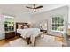 Bright bedroom featuring a wooden bed frame, bench, neutral decor, and abundant natural light from the large windows at 901 Hartford Ave, Charlotte, NC 28209