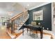 Inviting home office space featuring a sleek desk, a decorative mirror, and a staircase with an ornate wrought iron railing at 901 Hartford Ave, Charlotte, NC 28209