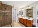 Bathroom featuring double vanity sinks with framed mirrors, a tile shower and earth tone floors at 10311 Windtree Ln, Charlotte, NC 28215