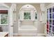 A bathroom featuring a tub with an archway, neutral paint, and a large window bringing the outdoors in at 10311 Windtree Ln, Charlotte, NC 28215
