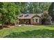 Charming brick home with a manicured lawn, covered porch, and mature trees at 10311 Windtree Ln, Charlotte, NC 28215