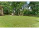 Lush backyard with mature trees, green lawn, and a wooden shed, providing a private outdoor retreat at 107 Glenmont Ct, Mooresville, NC 28117