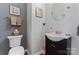 Charming half bath with a dark vanity, round mirror, and neutral decor at 107 Glenmont Ct, Mooresville, NC 28117