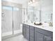 Modern bathroom featuring double sinks, sleek gray cabinets, and a glass-enclosed shower with marble-style tile at 11034 Engelmann Ln, Charlotte, NC 28269