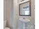 Elegant half bathroom featuring a pedestal sink with a decorative mirror and a modern toilet at 1195 Cavalier Ln, Rock Hill, SC 29730