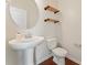 Modern powder room featuring a pedestal sink, wood shelves, and round mirror at 133 Yellowbell Rd, Mooresville, NC 28117