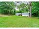 View of the single-story home with a wooden porch nestled in a grassy lawn and surrounded by lush trees at 1529 Stony Point Rd, Shelby, NC 28150