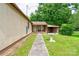 Exterior view of a home's side featuring a covered porch, lush greenery, and a serene birdbath at 1529 Stony Point Rd, Shelby, NC 28150
