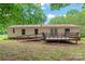 Back of home with a wooden deck, access ramp, white siding, and lush green trees in the background at 1773 Baldwin Ln, Lincolnton, NC 28092