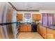 Galley-style kitchen with stainless steel refrigerator and oak cabinetry at 1825 Stroud Park Ct, Charlotte, NC 28206