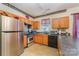 Galley-style kitchen with stainless steel refrigerator and oak cabinetry at 1825 Stroud Park Ct, Charlotte, NC 28206