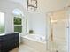 Bright bathroom features a soaking tub, glass enclosed shower and a decorative light fixture at 314 Southern Cross Ln, Matthews, NC 28105