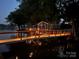 Atmospheric view of lighted walkway towards a lakeside building reflecting lights in the water at 4681 Dove Point Ln, York, SC 29745