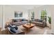 Bright living room showcasing modern sofas with blue pillows, a stylish coffee table, and natural light from large windows at 5002 Abode Lily Ln, Charlotte, NC 28227