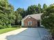 Single-story home with a long driveway and brick exterior accents in a wooded setting at 509 Settlers Grove Ln, Salisbury, NC 28146