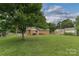 Lush backyard featuring a well-kept lawn, mature shade trees and exterior view of brick home at 6206 Clearwater Dr, Indian Trail, NC 28079