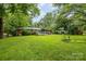 View of the backyard featuring a well maintained lawn, brick home, and a wooden deck at 6207 Robinson Church Rd, Charlotte, NC 28215