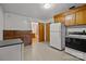 Functional kitchen with wooden cabinets, white appliances, and a door leading to another room at 6207 Robinson Church Rd, Charlotte, NC 28215