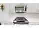 A modern kitchen features white cabinets, quartz countertops, and stainless steel appliances, including gas range and microwave at 7651 Fenn Way, Fort Mill, SC 29707