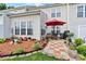 Landscaped backyard featuring a patio with a red umbrella, lush garden beds, and a well-maintained lawn at 8002 Mariners Pointe Cir, Denver, NC 28037