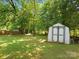 Backyard with a storage shed surrounded by lush greenery and a well-maintained lawn at 8030 Glencannon Dr, Charlotte, NC 28227