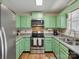 Cozy kitchen featuring updated stainless steel appliances and green cabinets at 8030 Glencannon Dr, Charlotte, NC 28227