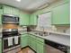 Cozy kitchen featuring updated stainless steel appliances and green cabinets at 8030 Glencannon Dr, Charlotte, NC 28227