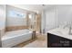 Modern bathroom featuring a double sink vanity, soaking tub, glass enclosed shower, and neutral tile flooring at 8400 Empress Ct, Charlotte, NC 28227