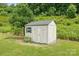A small shed with double doors and a window sits on a green lawn surrounded by trees at 8400 Empress Ct, Charlotte, NC 28227
