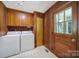 Cozy laundry room with wood paneling, ample cabinet space and white appliances at 967 Hilldale Dr, Lancaster, SC 29720