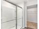 A full bathroom with a glass sliding shower door and a peek into a walk-in closet with wire shelving at 10127 Florentine Way, Charlotte, NC 28214