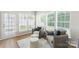 Bright sitting room with two chairs, two stools, large windows, hardwood floors, and area rug at 10225 Alexander Martin Ave, Charlotte, NC 28277