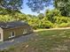 View of a spacious backyard with well-maintained lawn, mature trees and gravel area for additional parking at 103 Garfield Ave, Albemarle, NC 28001