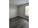 A simple bedroom with dark wood-style floors and a bright window view at 1104 Plaza Walk Dr, Charlotte, NC 28215