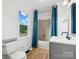 Bathroom with white walls, blue shower curtain, toilet, light wood floors, and gray vanity with dark hardware at 1238 Carl Allen Rd, Edgemoor, SC 29712