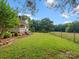 Spacious side yard featuring manicured lawn, brick-lined flower bed, and picturesque view of green pasture at 1238 Carl Allen Rd, Edgemoor, SC 29712