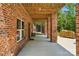Covered brick patio has wood ceiling, brick columns and access to wooded backyard at 16525 Tulloch Rd, Charlotte, NC 28278