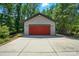 Detached garage with concrete parking, a red garage door, and neutral-tone siding nestled among verdant trees at 16525 Tulloch Rd, Charlotte, NC 28278
